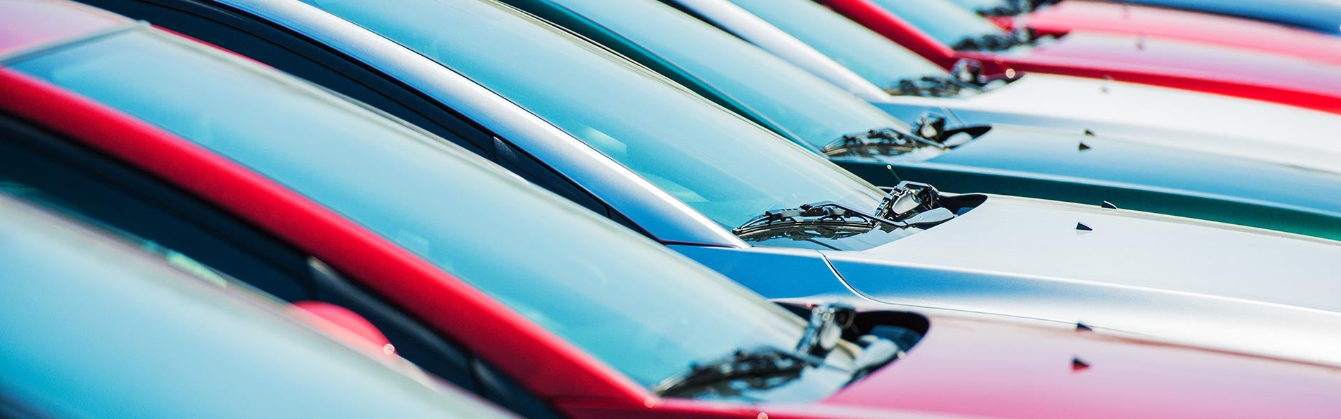 Row of colorful new cars parked in a dealership lot.